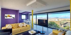 a living room with a yellow couch and a large window at Sand Volcano Villa 2 in La Oliva