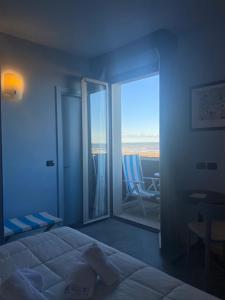 una camera con letto e porta scorrevole in vetro di Hotel Corallo Rimini a Rimini