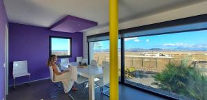 a woman sitting at a table in a room with a view at Sand Volcano Villa 2 in La Oliva