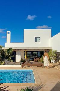 a woman in a white dress walking in front of a house at Sand Volcano Villa 2 in La Oliva