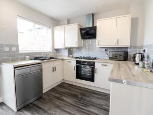 una cocina con armarios blancos y electrodomésticos de acero inoxidable en 4 Plas Newydd, en Llandudno