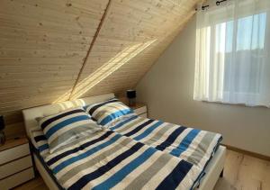 a bedroom with a bed with striped pillows and a window at Domek Maciej in Kopalino