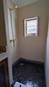 a bathroom with a window and a black tile floor at RIAD DAR En-Nawat in Marrakesh