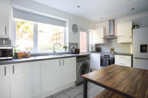 a kitchen with white cabinets and a wooden table at Fully Refurbished North Belfast Home in Belfast