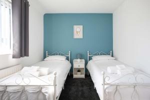 2 łóżka w pokoju z niebieską ścianą w obiekcie Fully Refurbished North Belfast Home w mieście Belfast