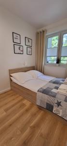a bedroom with a bed and a window at Dwie Sosny Apartamenty Ostrowski in Ustronie Morskie