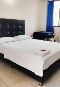 duże białe łóżko w pokoju z niebieskimi zasłonami w obiekcie Hotel Costa Caribe w mieście Barranquilla