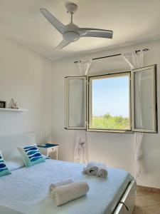 - une chambre avec un lit, un ventilateur de plafond et une fenêtre dans l'établissement 200 m from the beach - WiFi - Air Conditioning, à San Pietro in Bevagna