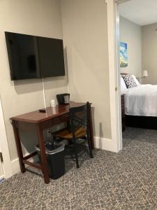 um quarto de hotel com uma secretária, uma televisão e uma cama em Country Squire Inn and Suites em New Holland