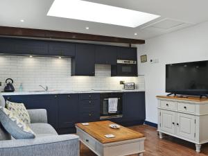 a kitchen with navy blue cabinets and a tv at The Dairy - Uk30867 in St Bees