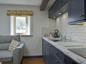 eine Küche mit blauen Schränken, einem Waschbecken und einem Fenster in der Unterkunft The Dairy - Uk30867 in St Bees