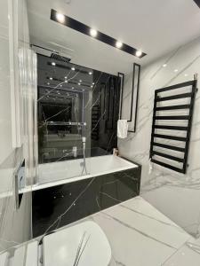 a white bathroom with a tub and a mirror at Apartamenty Centrum Apartament X1 in Mszana Dolna