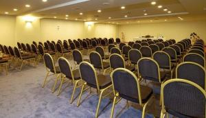 a room with rows of chairs and a man standing in the background at Giannoulis - Santa Marina Plaza (Adults Only) in Agia Marina Nea Kydonias