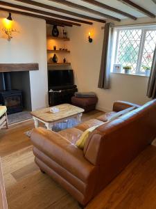 a living room with a leather couch and a table at Cosy Flint Cottage in Eastbourne