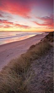 a sunset on a beach with the ocean at Highthel Holiday Home by the Northumberland Coast in Morpeth