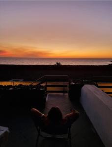 una persona sentada en una silla viendo la puesta de sol en Perla Nera I DAMMUSI DI SCAURI en Pantelleria