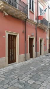 a pink building with three doors and a balcony at B&B Manzoni Resort in Brindisi
