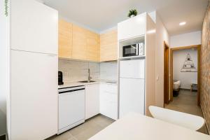 a kitchen with white cabinets and a white refrigerator at dobohomes - Horcajuelo in Madrid