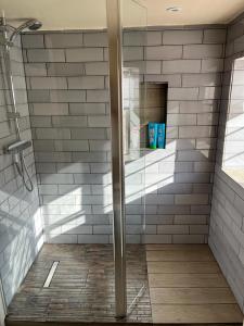 a shower with a glass door in a bathroom at Cosy Flint Cottage in Eastbourne