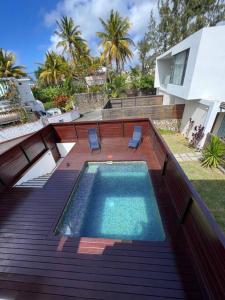 a swimming pool with two chairs and a house at Villa Pereybère White Pearl in Pereybere