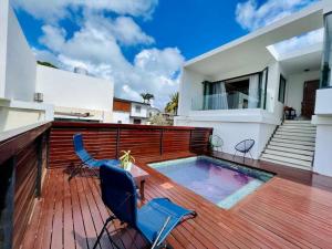 a deck with a pool and two chairs and a house at Villa Pereybère White Pearl in Pereybere