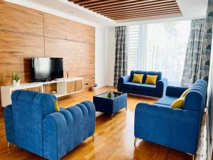 a living room with two blue couches and a tv at Villa Pereybère White Pearl in Pereybere