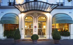 ein Geschäft vor einem Gebäude mit einem großen Eingang in der Unterkunft Hôtel Raspail Montparnasse in Paris