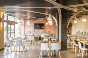 a dining room with tables and white chairs at ibis Styles Meaux Centre in Meaux