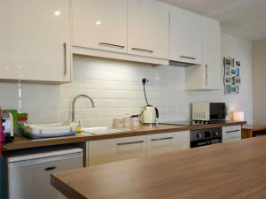 a kitchen with white cabinets and a sink at Marina Apartment in Y Felinheli