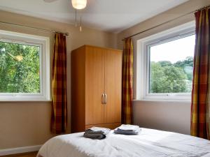 a bedroom with a bed and two windows at Marina Apartment in Y Felinheli