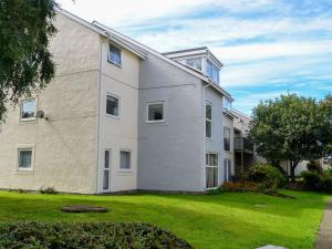 a large white building with a grass yard at Marina Apartment in Y Felinheli