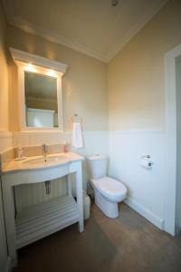 een badkamer met een wastafel, een toilet en een spiegel bij CatsWhiskers in Graaff-Reinet