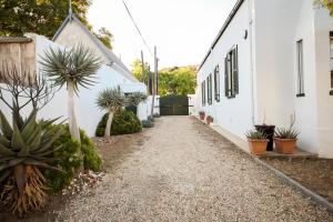 a gravel path next to a white building with plants at CatsWhiskers in Graaff-Reinet
