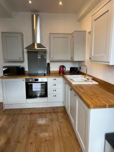 cocina con armarios blancos y encimera de madera en Beautiful 2 bedroom with patio and amazing views, en Hebden Bridge