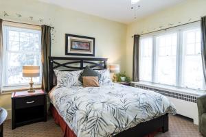 a bedroom with a bed and two windows at The Inn on Bay in Gravenhurst