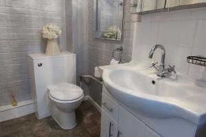 Baño blanco con aseo y lavamanos en Windsor Cottage: Cosy, Charming, Full of Character, en Windsor