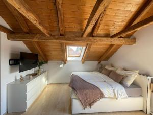 Schlafzimmer mit einem Bett, einem TV und Holzdecken in der Unterkunft BullsLiving Seeapartment 2 AM CORSO in Velden am Wörthersee
