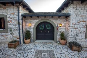 a stone house with a black door and potted plants at Patriko Estate in Epirus in Térovon