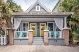 a house with a yellow front door and palm trees at Gambino Getaway Shotgun style apt in the heart of Ybor City in Tampa