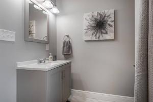 a white bathroom with a sink and a mirror at Gambino Getaway Shotgun style apt in the heart of Ybor City in Tampa