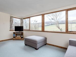 a living room with a chair and a tv and windows at The Mill - Uk31512 in Tomnavoulin