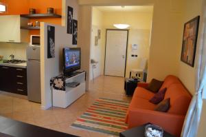a living room with an orange couch and a television at Casa dei Limoni in Toscolano Maderno