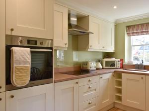uma cozinha com armários brancos e um micro-ondas em 3 The Reading Room Cottages - Uk31802 em Barningham