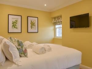 um quarto com uma cama branca e uma televisão de ecrã plano em 3 The Reading Room Cottages - Uk31802 em Barningham