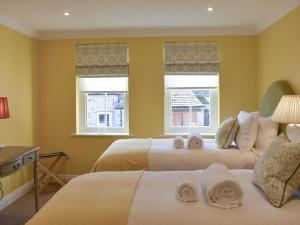 a bedroom with two beds and two windows at 3 The Reading Room Cottages - Uk31802 in Barningham