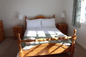 a bedroom with a wooden bed and two night stands at Farmston Lodge in Callander