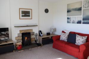 a living room with a red couch and a fireplace at Farmston Lodge in Callander