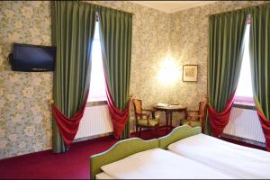 a bedroom with a bed and a tv and curtains at Hotel Hohenstauffen in Salzburg