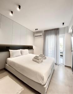 a white bedroom with a large bed with towels on it at Seafront Apartment by C2C Architects in Kalívia Thorikoú