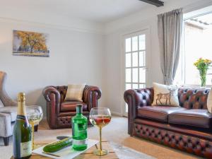 a living room with two leather couches and wine glasses at The Cottage in Shipdham